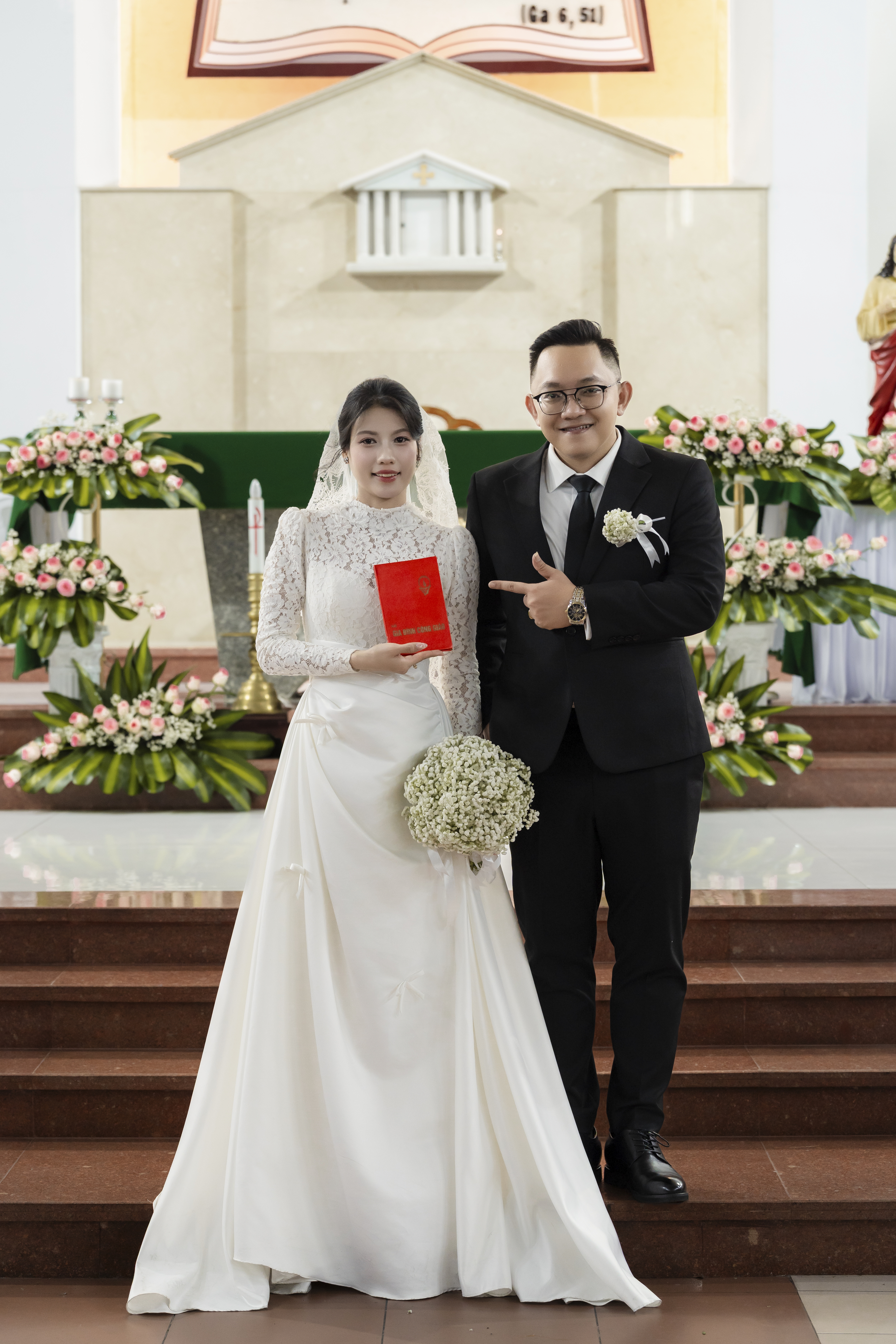Trúc & Văn hân hoan cầm trên tay Sổ Gia Đình Công Giáo trước Bàn thờ Chúa